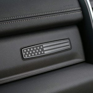 Peut inclure: Gros plan sur un intérieur de voiture en cuir noir avec un emblème de drapeau américain argenté.