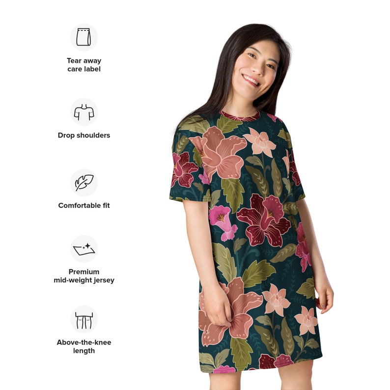 May include: A dark green above-the-knee length dress with a floral print featuring pink, red, and white flowers. The dress has a comfortable fit and drop shoulders. It is made from a premium mid-weight jersey fabric.