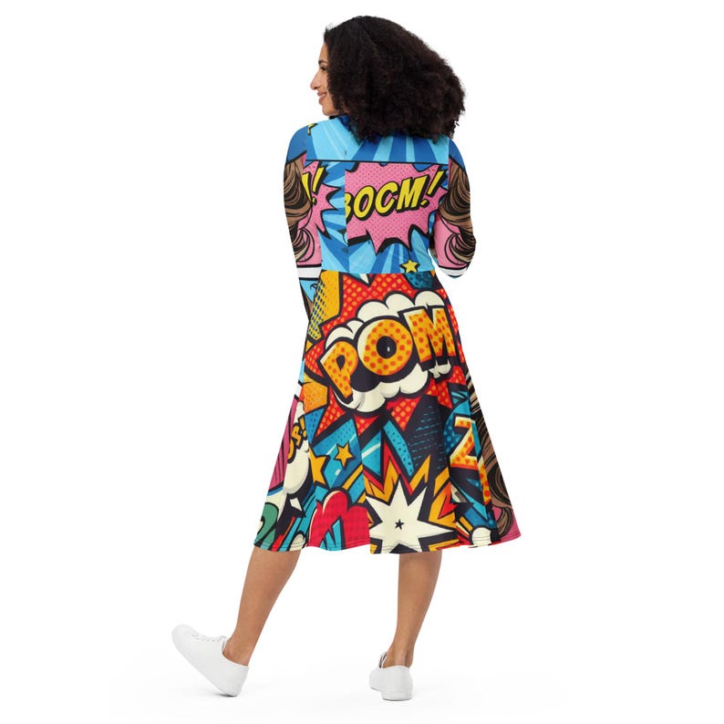 May include: A long-sleeve dress featuring a vibrant comic book design. The dress showcases bold colors, including blue, pink, yellow, and red, with the words "BOOM!" and "POM" in speech bubbles. The dress has a flared skirt and is worn with white sneakers.