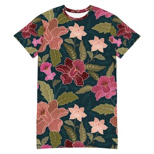 May include: A dark teal t-shirt with a floral print featuring pink, red, and peach flowers. The flowers are arranged in a repeating pattern on a dark teal background.