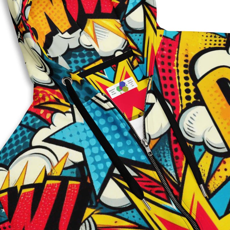 Puede incluir: Una sudadera con capucha de cremallera completa con un estampado de c&oacute;mic colorido en amarillo, rojo, azul y negro. La sudadera tiene una cremallera negra y cordones negros.
