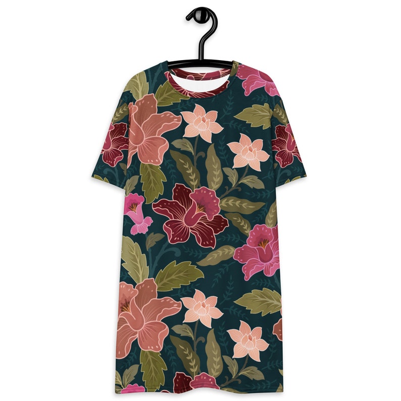 May include: A teal blue t-shirt with a floral print featuring pink, red, and white flowers on a dark green background.
