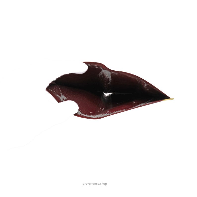 May include: The inside of a burgundy leather wallet with a gold accent. The wallet is open and the inside is visible.