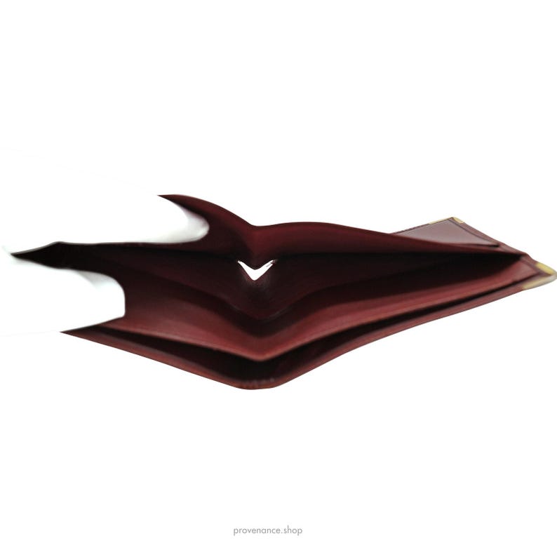 May include: A burgundy leather wallet with multiple folds, open to reveal the inside.