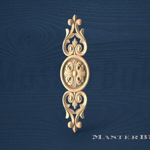 May include: A carved wooden decorative element with an ornate design. The piece features a central circular medallion with floral details, flanked by scrolling and stylized leaf shapes. The background is a dark blue wood grain.