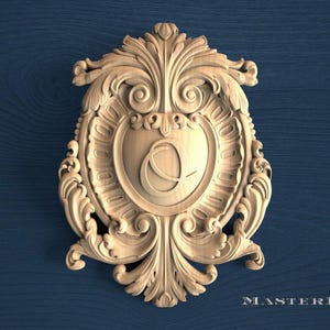 May include: A light-colored wooden plaque featuring an intricate carved border with scrolling acanthus leaf patterns and a central shield shape containing the letter O. The text MASTERBUK is visible in the bottom right corner of the image.