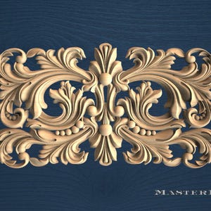 May include: A rectangular light-coloured wooden carving featuring symmetrical acanthus leaf scrolls and floral motifs. The design includes central vertical elements and small spherical accents integrated into the intricate, carved relief pattern.