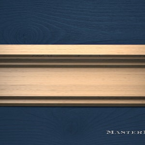 May include: A close-up of a wooden molding with a light brown finish, set against a dark blue wood grain background. The molding has a layered design with a flat top and a grooved lower section. The text "MASTERBUK" is visible in the bottom right corner.