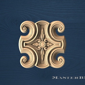 May include: A carved wooden decorative element with a symmetrical design. The piece features a central floral motif surrounded by stylized scrollwork and a cross-like pattern. The background is a dark blue wood grain.