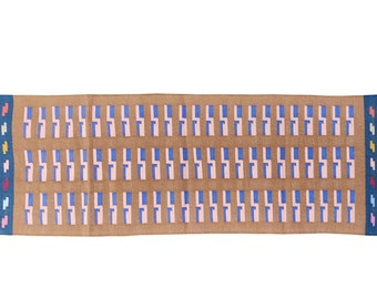 May include: A brown rectangular rug with a geometric pattern of blue, pink, and white squares. The rug has fringe on the ends.