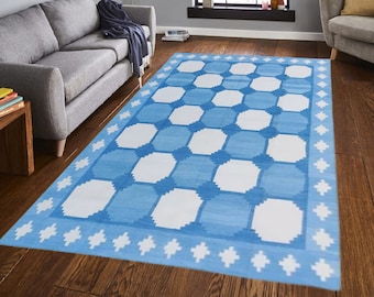 Puede incluir: Una alfombra azul y blanca con un diseño geométrico. La alfombra tiene un borde blanco con un patrón de estrellas azules.