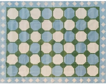 May include: A blue and white rug with a green geometric pattern. The rug has a white border with a blue and white diamond pattern.