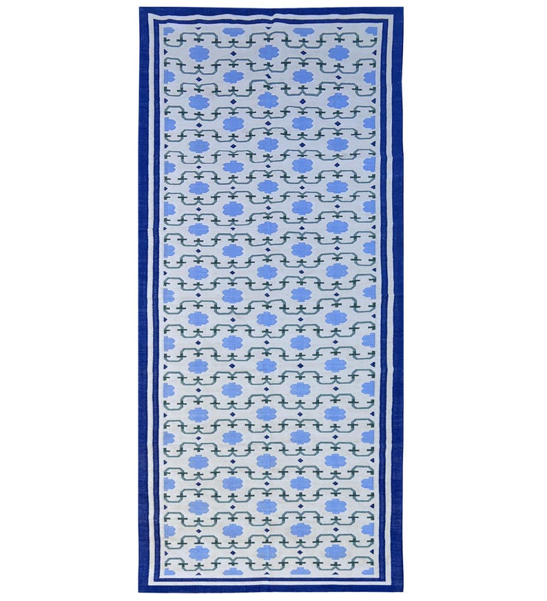 May include: A blue and white patterned rug with a blue border. The pattern features a repeating design of stylized flowers and geometric shapes.