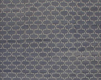 Puede incluir: Una alfombra estampada azul y blanca. La alfombra presenta un diseño geométrico repetitivo en color crema claro sobre un fondo azul oscuro. El patrón es una serie de formas interconectadas, creando una apariencia texturizada.