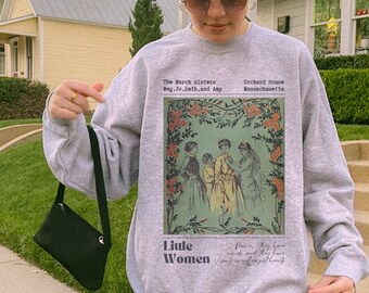 Könnte beinhalten: Ein graues Sweatshirt mit einer Vintage-Illustration von vier Frauen in einem floralen Rahmen. Der Text "The March sisters Meg. Jo. Beth, and Amy" und "Orchard House Massachusetts" ist über der Illustration gedruckt. Der Text "Little Women" ist unter der Illustration gedruckt.