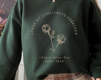 May include: A dark green sweatshirt with a quote from Edgar Allan Poe that reads "Leave my loneliness unbroken" with two roses in the center. The quote is in a cream color.