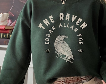 May include: A dark green sweatshirt with a white graphic print of a raven and the text "THE RAVEN EDGAR ALLAN POE ~1845~"