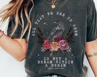 Könnte beinhalten: Ein dunkelgraues T-Shirt mit einem grafischen Aufdruck eines Rabens und Blumen. Der Text "All that we see or seem is but a dream within a dream - Edgar Allan Poe" ist auf dem T-Shirt aufgedruckt.