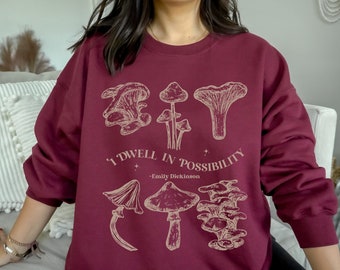 May include: Burgundy sweatshirt with a graphic of mushrooms and the quote "I dwell in possibility - Emily Dickinson".