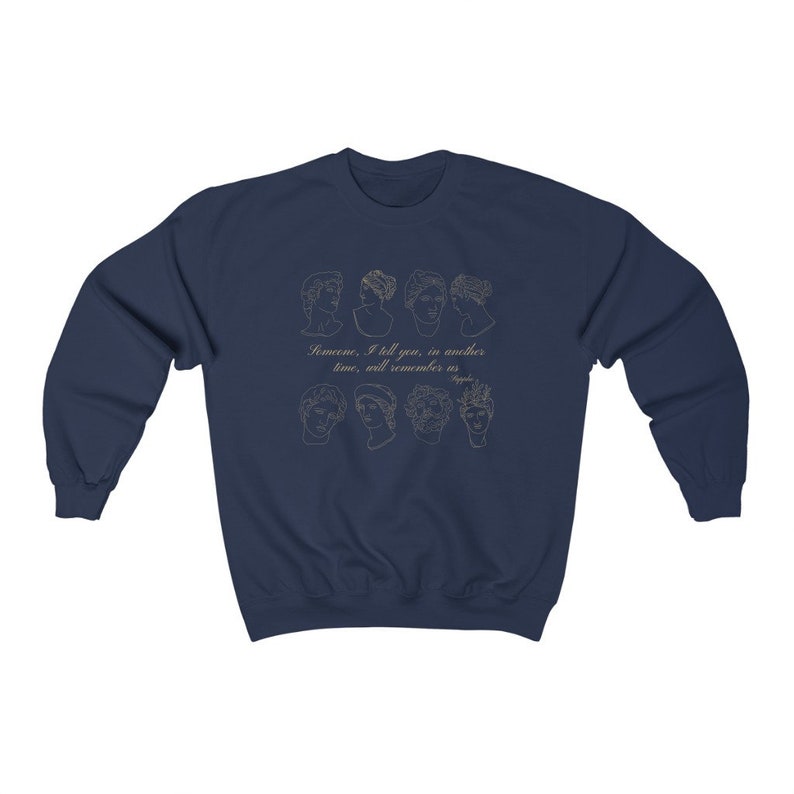 Pode incluir: Camisola azul marinho com um contorno dourado de oito rostos e o texto "Algu&eacute;m, eu te digo, em outro tempo, se lembrar&aacute; de n&oacute;s."