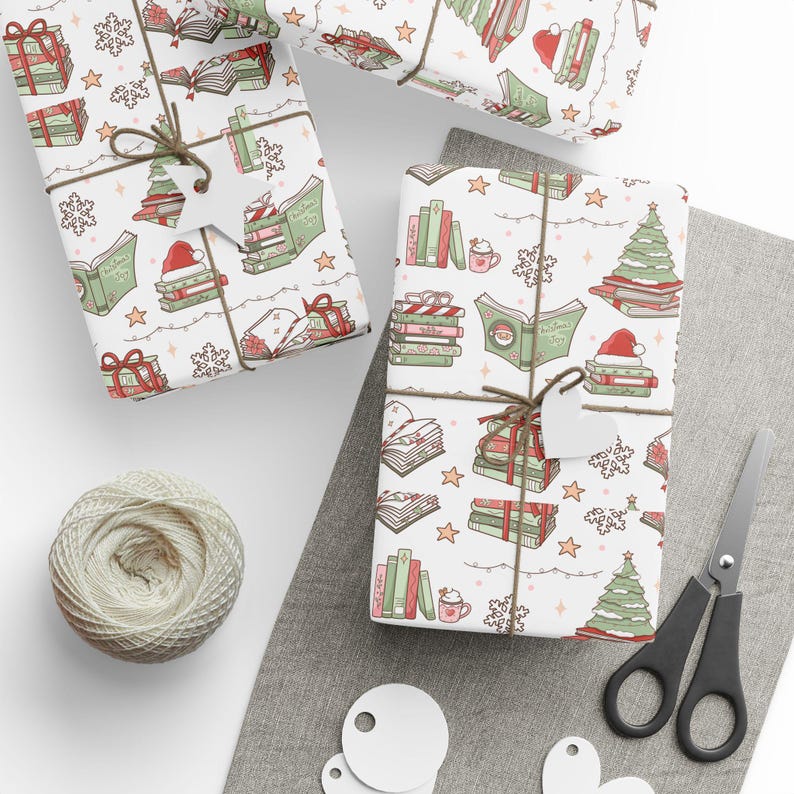 May include: Three wrapped gifts with a festive book-themed pattern. The wrapping paper features illustrations of books, Christmas trees, snowflakes, and Santa hats. Each gift is tied with twine and a blank tag. A ball of twine, scissors, and blank tags are also visible.