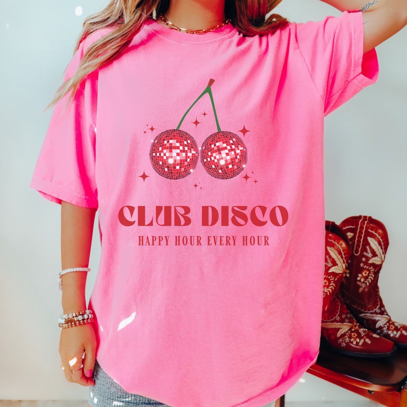 May include: Pink t-shirt with a red cherry graphic featuring disco ball cherries and the text "Club Disco Happy Hour Every Hour".