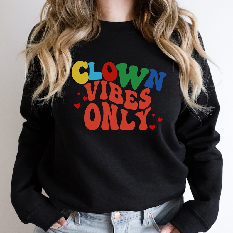 Może przedstawiać: Czarny sweter z napisem "CLOWN VIBES ONLY" w kolorowych retro literach z czerwonymi sercami.