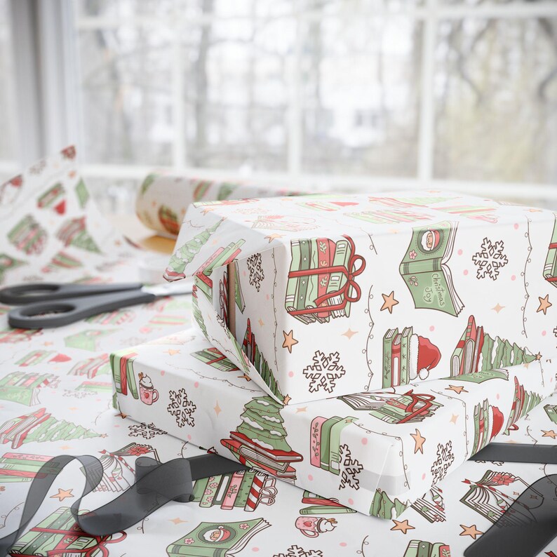 May include: Two wrapped gifts with white wrapping paper featuring a festive pattern of books, Christmas trees, snowflakes, and stars. A pair of scissors and a roll of matching wrapping paper are visible in the background. A black ribbon is in the foreground.