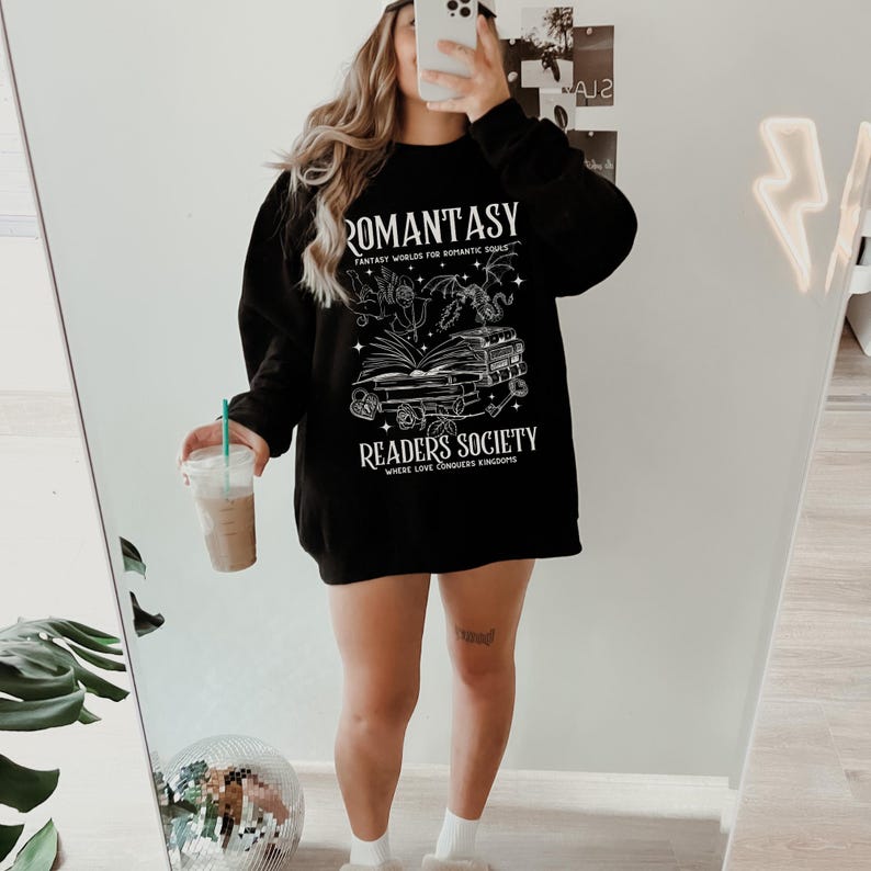 May include: Black sweatshirt with a white graphic design featuring a book, a dragon, and the text "Romantasy: Fantasy Worlds for Romantic Souls" and "Readers Society: Where Love Conquers Kingdoms".