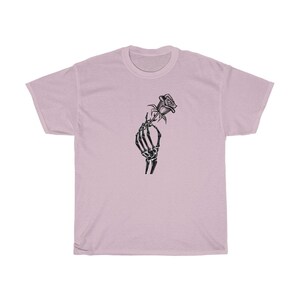 K&ouml;nnte beinhalten: Ein hellrosa T-Shirt mit einem schwarz-wei&szlig;en Motiv einer Skeletthand, die eine Rose h&auml;lt.