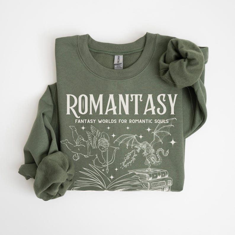 May include: A green sweatshirt with the text "ROMANTASY" and the words "Fantasy Worlds for Romantic Souls". The sweatshirt features a graphic of a winged cherub with a bow and arrow, a dragon, and a stack of books.