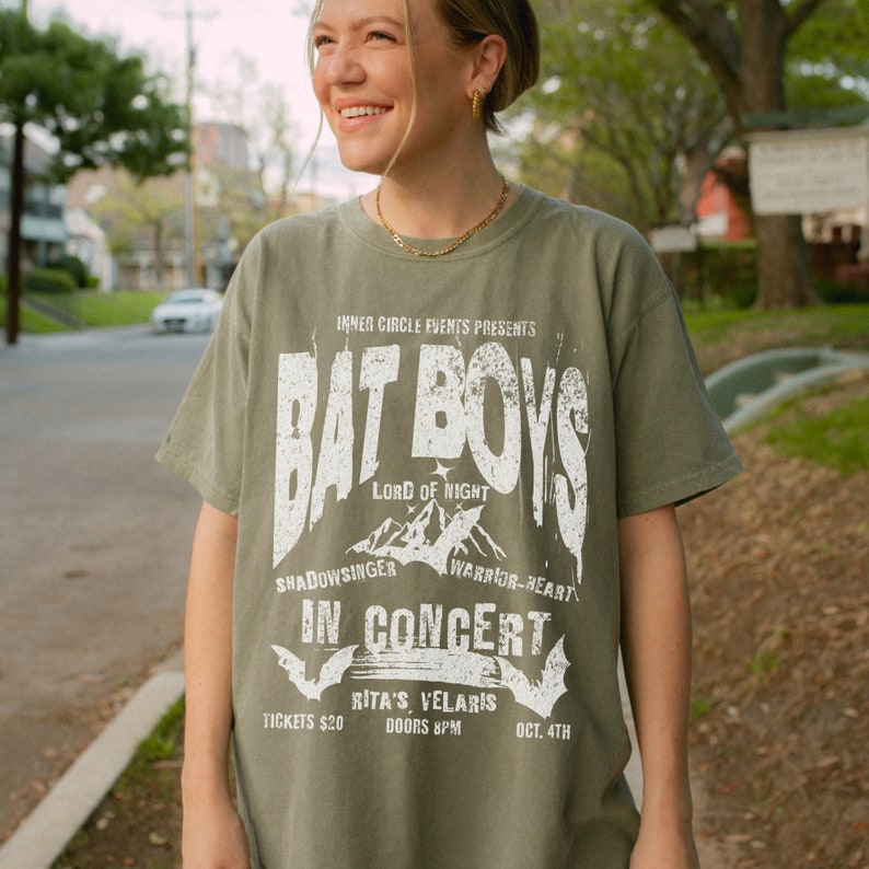K&ouml;nnte beinhalten: Ein gr&uuml;nes T-Shirt mit einem wei&szlig;en Grafikdruck einer Band namens "Bat Boys" mit dem Text "Lord of Night", "Shadowsinger", "Warrior-Heart", "In Concert", "Rita's Velaris", "Tickets 20&euro;", "Doors 8PM" und "Oct. 4th".