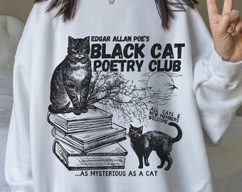 May include: White sweatshirt with a black and white graphic print of a black cat sitting on a stack of books. The graphic includes the text "Edgar Allan Poe's Black Cat Poetry Club" and "...as mysterious as a cat".