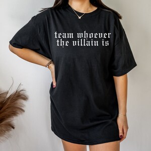 May include: Black oversized t-shirt with the text "team whoever the villain is" in white gothic font.