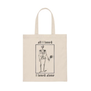 Peut inclure: Un sac fourre-tout beige avec une illustration en noir et blanc d'un squelette tenant une rose. Le texte "all I loved I loved alone" est imprim&eacute; sur le sac.