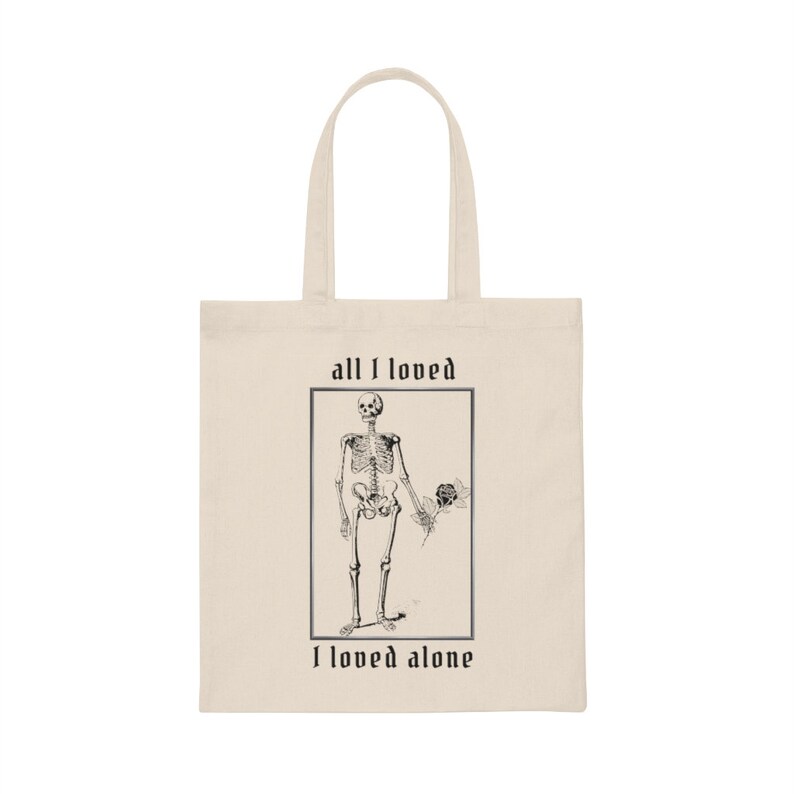 Peut inclure: Un sac fourre-tout beige avec une illustration en noir et blanc d'un squelette tenant une rose. Le texte "all I loved I loved alone" est imprim&eacute; sur le sac.