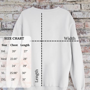 Może przedstawiać: Tabela rozmiar&oacute;w dla bluzy z wymiarami w calach dla klatki piersiowej i długości. Tabela pokazuje rozmiary od S do 2XL.