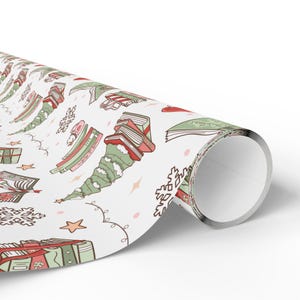 May include: White wrapping paper roll with a repeating pattern of Christmas trees, books, snowflakes, stars, and hearts in red, green, and pink. The paper is rolled up, showing the pattern on the surface.