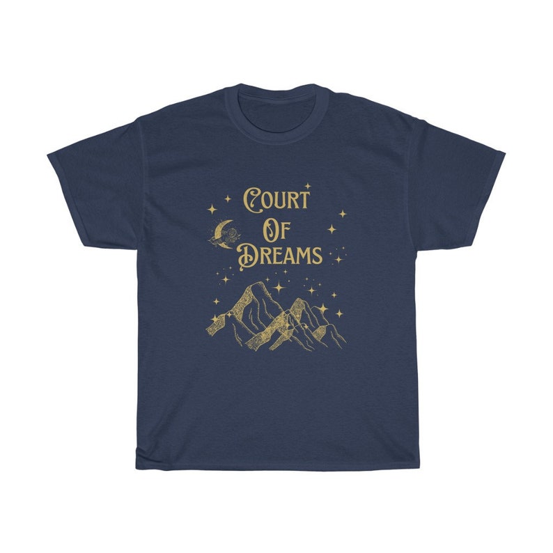May include: A navy blue t-shirt featuring a gold graphic of mountains, a crescent moon, and stars. The text "COURT OF DREAMS" is printed in gold on the shirt.