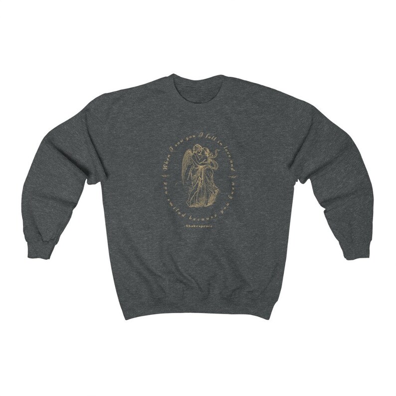 May include: A dark heather grey sweatshirt with a gold graphic of two angels embracing. The graphic is surrounded by a circle with the text "When I saw you I fell in love, and love'd you, and must love you still" and "Shakespeare".