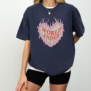 May include: A navy blue t-shirt with a graphic of a pink heart with flames and the text "WORLD ENDER" in red.