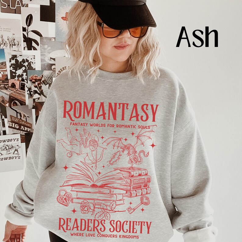 May include: Gray sweatshirt with a red graphic print of a book, a dragon, and an angel. The text on the graphic reads "Romantasy Fantasy Worlds for Romantic Souls" and "Readers Society Where Love Conquers Kingdoms".