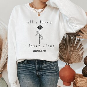 May include: White sweatshirt with a black rose and the text "all i loved i loved alone Edgar Allan Poe".