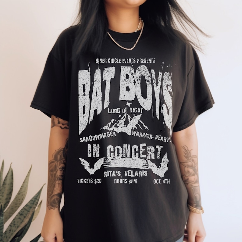K&ouml;nnte beinhalten: Schwarzes T-Shirt mit einem wei&szlig;en Grafikdruck einer Band namens "Bat Boys" im Konzert. Die Grafik enth&auml;lt den Bandnamen, "Lord of Night", "Shadowsinger", "Warrior-Heart" und das Datum "Oct. 4th".