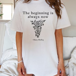 May include: White t-shirt with a black graphic print that reads "The beginning is always now" and "~Mary Shelley".