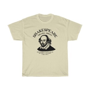 May include: A beige t-shirt featuring a black graphic of William Shakespeare. The graphic includes the text "Shakespeare, Drama Queen, Specialising in Love, Death, Revenge & Jealousy - Since 1564 - "