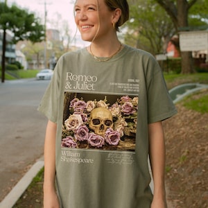 May include: Green t-shirt with a graphic print of a skull surrounded by pink roses. The text "Romeo & Juliet" and "William Shakespeare" are printed on the shirt.