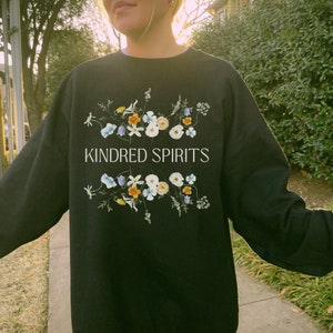 May include: Black sweatshirt with a floral design and the text "KINDRED SPIRITS" in white.