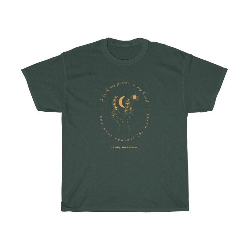 May include: A dark green t-shirt with a gold circle design featuring a moon, sun, and hands holding a branch with leaves. The text inside the circle reads "I took my power in my hand and went against the world." - Emily Dickinson.
