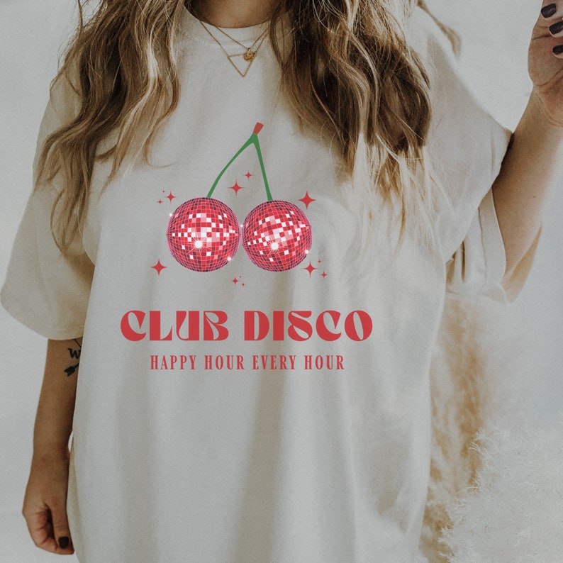 May include: White t-shirt with a red cherry graphic featuring a disco ball design. The text "Club Disco" and "Happy Hour Every Hour" is printed in red.